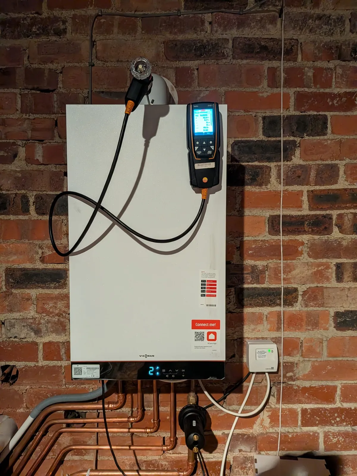 Viessmann boiler on an exposed brick wall with new copper pipework, a flue gas analyser connected for a combustion test